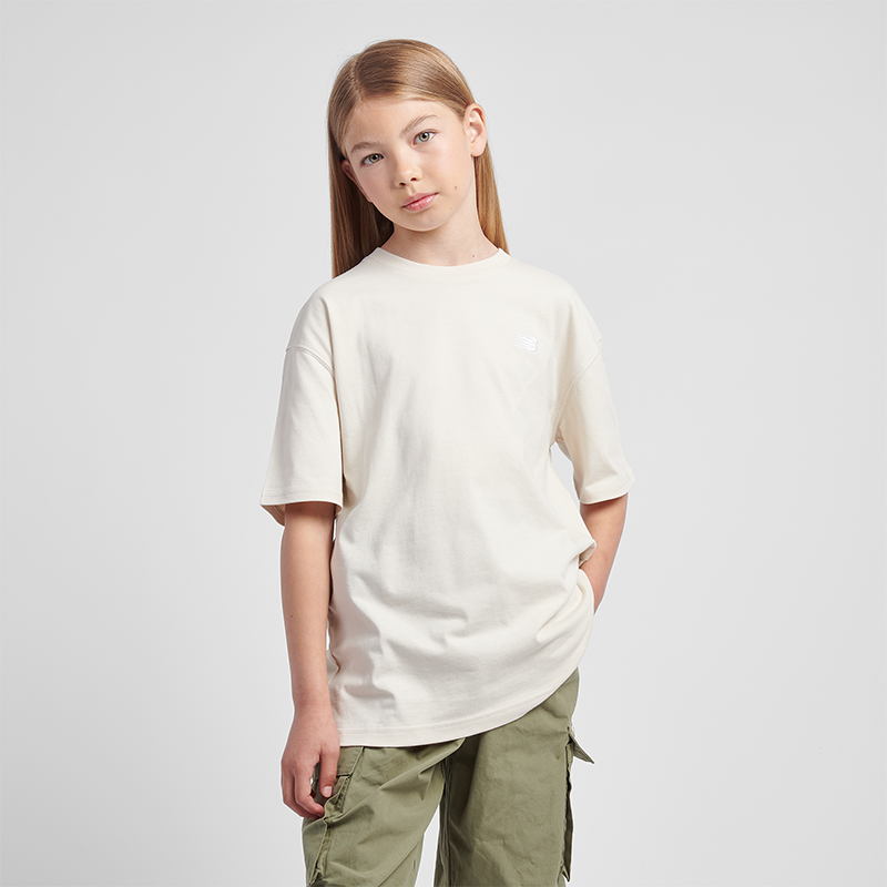 

Detské tričko New Balance LAKG0001LIN – béžové